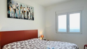 A hotel room with a large bed, a painting on the wall, a window with a view, and a nightstand with a lamp. - Spacious villa in El Ràfol d'Almúnia (El Ràfol d'Almúnia)