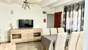 A living room with a TV, wooden furniture, and a ceiling fan. - Cozy 2-bedroom bungalow in Els Poblets with Wi-Fi and parking (Denia)