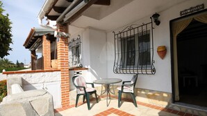 A patio with two chairs and a table, a brick wall, and a metal gate. - Cozy 2-bedroom bungalow in Els Poblets with Wi-Fi and parking (Denia)