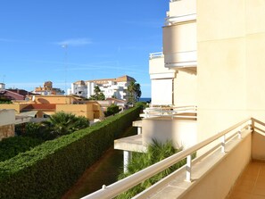 A residential building with a balcony, a well-maintained hedge, and a clear view of the sea and other buildings in the background. - Seafront apartment with pool and parking in Denia - Sleeps 8 (Denia)