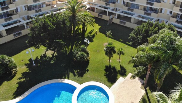 A multi-story hotel with balconies, a central courtyard with palm trees, and two swimming pools. - Charming 3-bedroom apartment with terrace and garden access in Denia (Denia)
