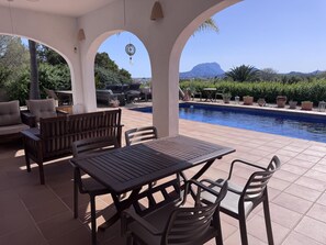 An outdoor patio with a pool, seating, and a view of a mountain.
