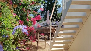 Un escalier menant à un niveau supérieur, entouré d’un jardin où poussent différentes plantes et fleurs.