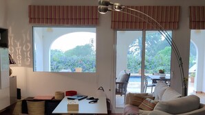 Un salon avec un canapé, une table et une grande fenêtre donnant sur un jardin.