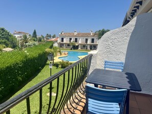 A balcony with a view of a swimming pool, a building with a white facade, and a blue chair. - Cozy Townhouse in Quiet Area (Denia)