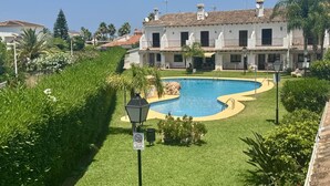 A pool surrounded by well-maintained grass and a building with multiple balconies. - Cozy Townhouse in Quiet Area (Denia)
