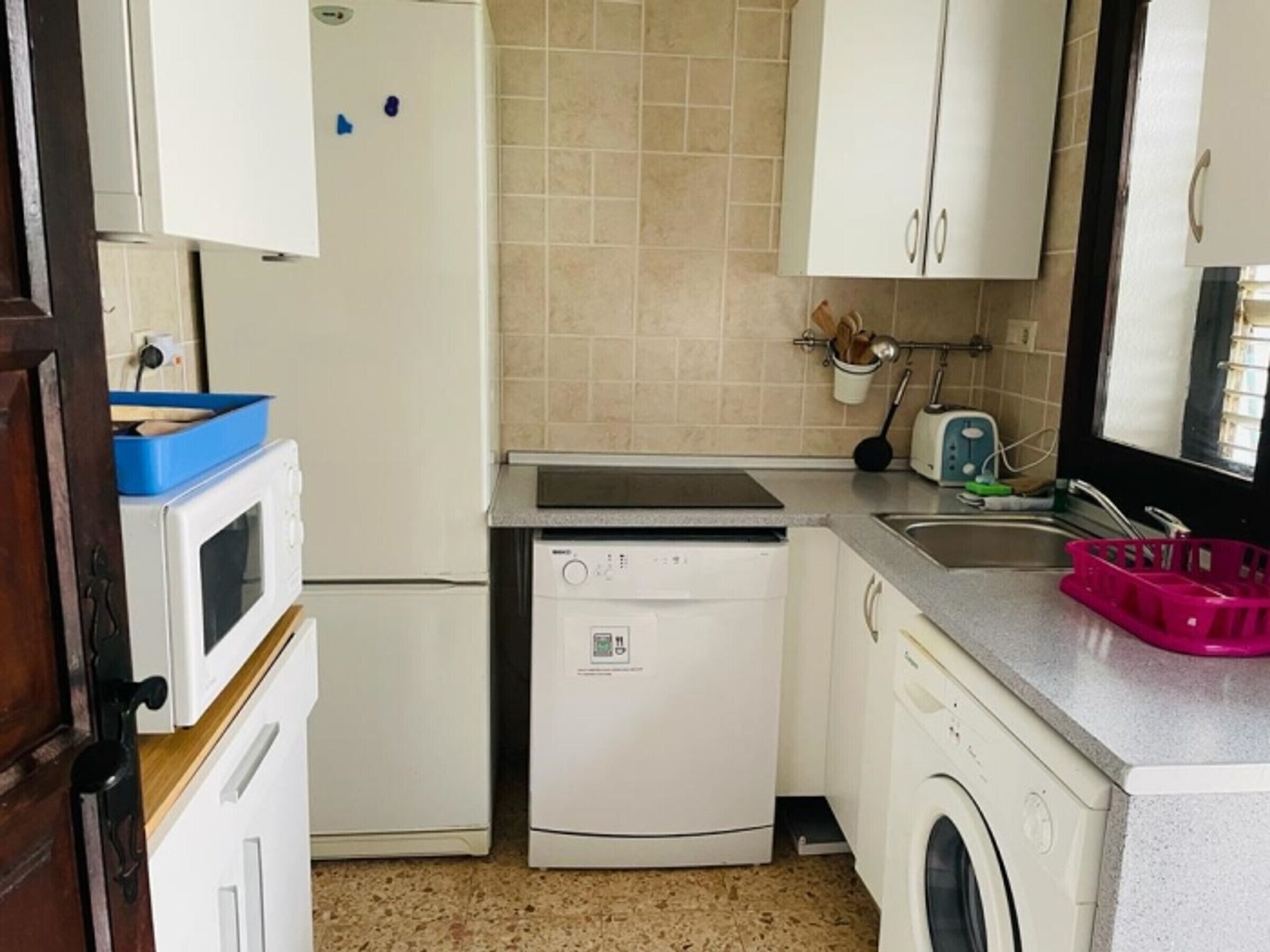 Uma cozinha compacta com micro-ondas, lava-louças e máquina de lavar roupa.