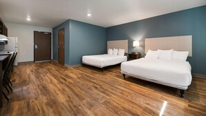 Ein Hotelzimmer mit zwei Betten, einem Schreibtisch und einer Küchenzeile.
