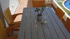Et bord med stole, en potteplante og en dekorativ lampe på en udendørs terrasse.
