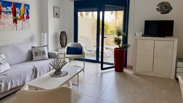A modern living room with a sofa, a coffee table, a TV, a potted plant, and a sliding glass door leading to a balcony. - Modern apartment in Denia, 2 bedrooms, beachfront (Denia)