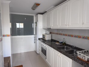 A kitchen with white cabinets, a microwave, a toaster, and a sink. - Seaside apartment in Denia with pet-friendly, parking and air conditioning (Denia)