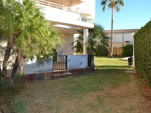 A two-story building with a covered outdoor area, palm trees, and a well-maintained lawn.