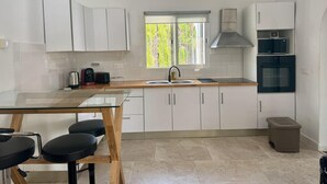 A modern kitchen with white cabinets, a stainless steel range hood, a double sink, and a built-in microwave. - Modern house near beach, pool, WiFi, air conditioning (Denia)