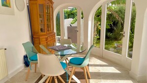 A dining area with a glass table, four chairs, and a wooden cabinet. - Modern house near beach, pool, WiFi, air conditioning (Denia)