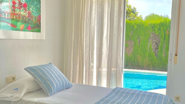 A hotel room with a bed, a painting on the wall, and a view of a swimming pool. - Modern house near beach, pool, WiFi, air conditioning (Denia)