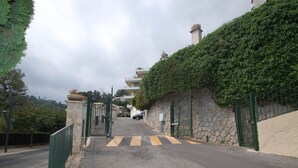 A paved pathway leading to a gated entrance with a stone wall and greenery on one side. - Spacious 3P with terrace and pool in Menton (Menton)