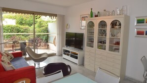 A living room with a TV, a dining table, and a glass cabinet. - Spacious 3P with terrace and pool in Menton (Menton)