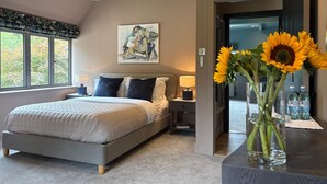 Quarto moderno com uma cama grande, uma mesa de cabeceira, um quadro na parede e um vaso de girassóis sobre uma mesa.