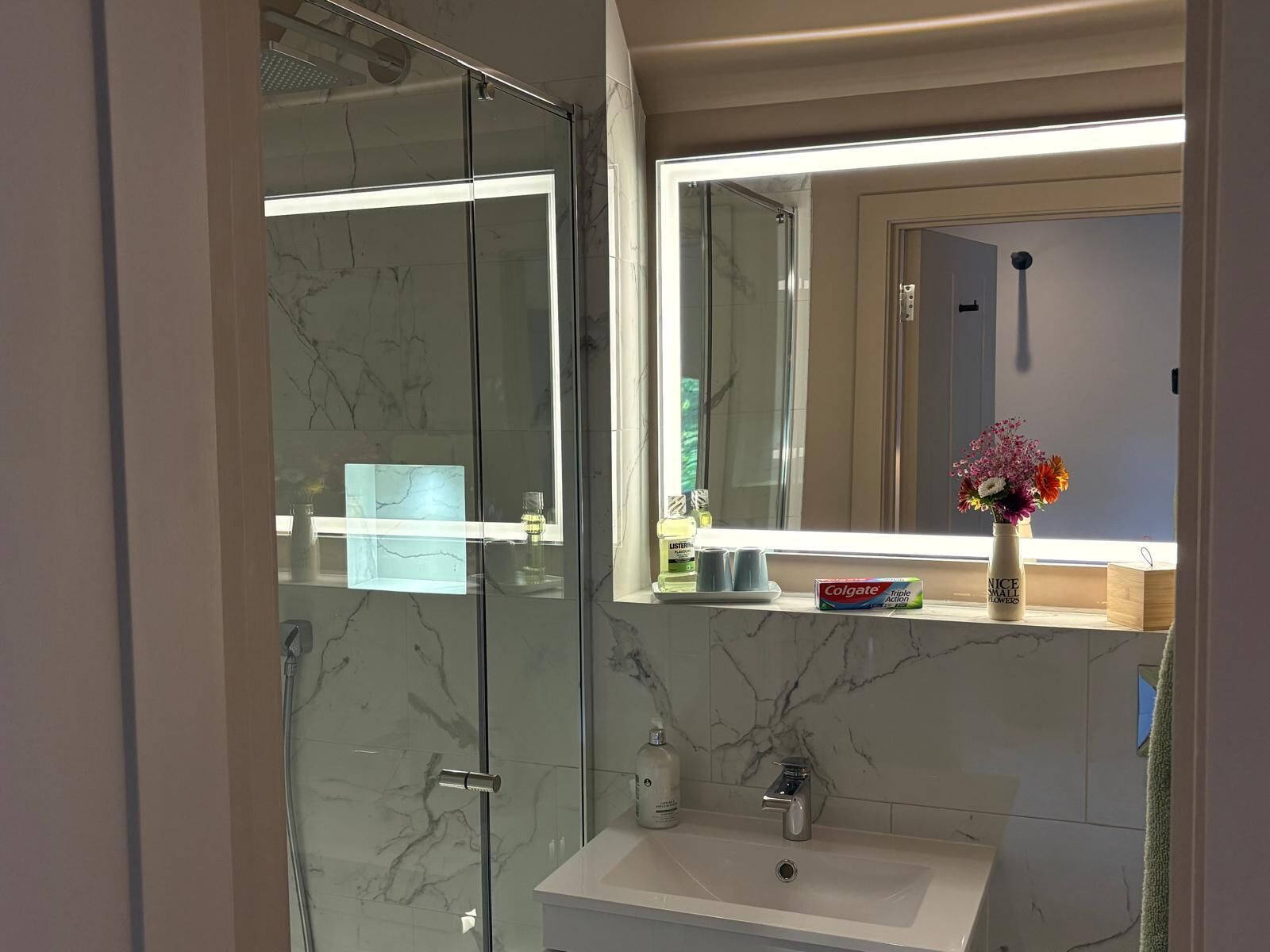 A modern bathroom with a glass shower enclosure, a white sink, and a mirror above the sink.