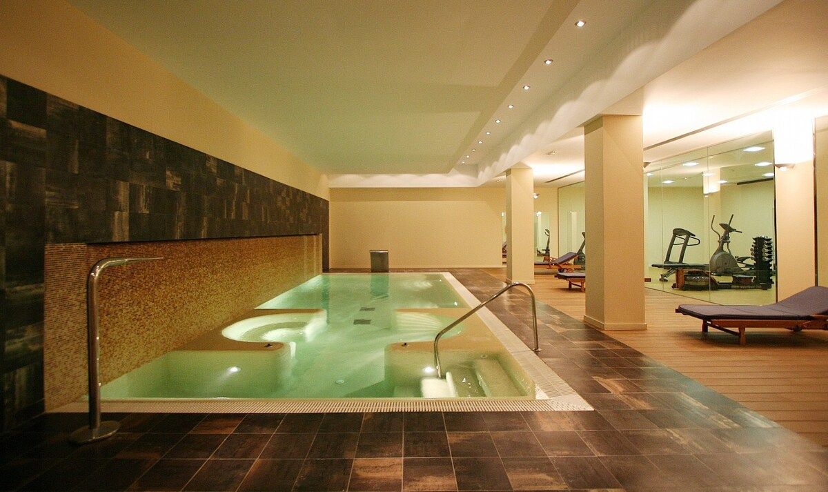 A spa area with a large hot tub, exercise equipment, and a wooden floor.