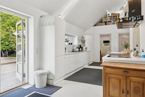 A modern kitchen with white cabinetry, a wooden countertop, and a view of the outdoors.