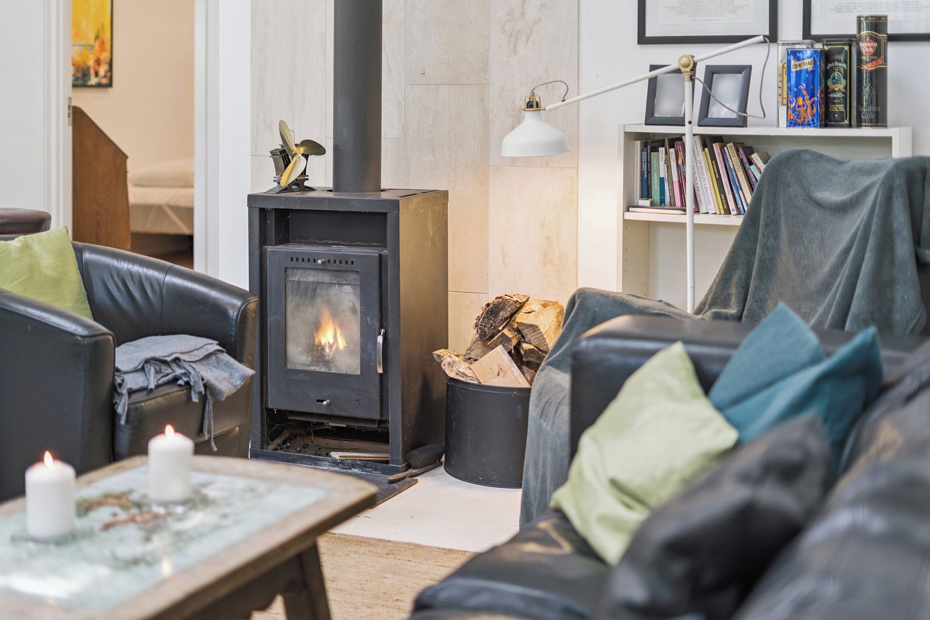 Una sala de estar acogedora con chimenea, sofá de cuero y una estantería.