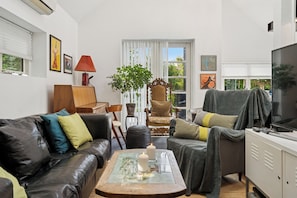 A living room with a leather couch, a wooden coffee table, a television, and a cabinet.