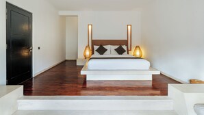 A bedroom with a bed, bedside lamps, a dark door, and a staircase. - The Seminyak Suites Private Villas  (Seminyak)