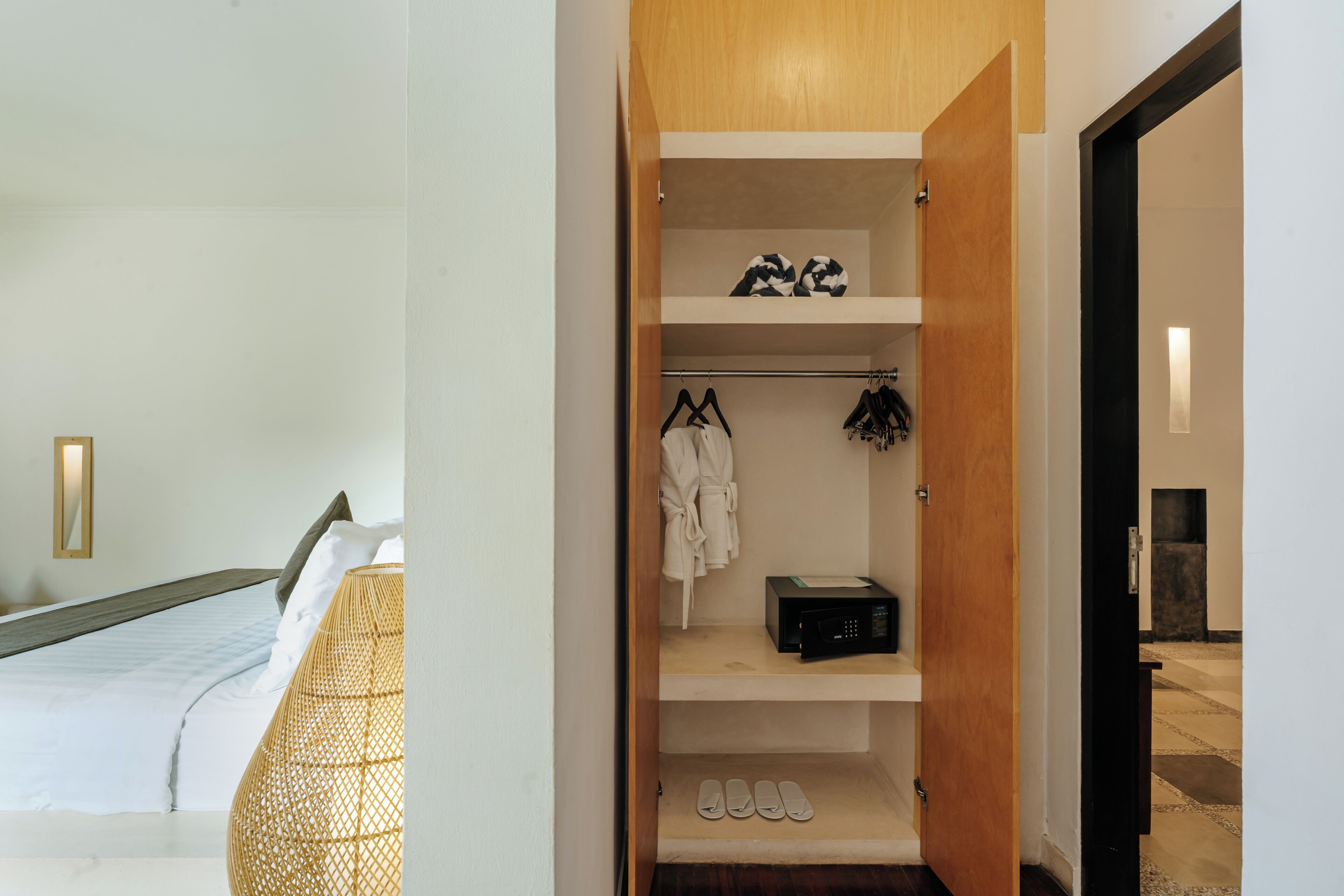 Una habitación de hotel con una cama, un armario con zapatos y un albornoz, y un microondas.