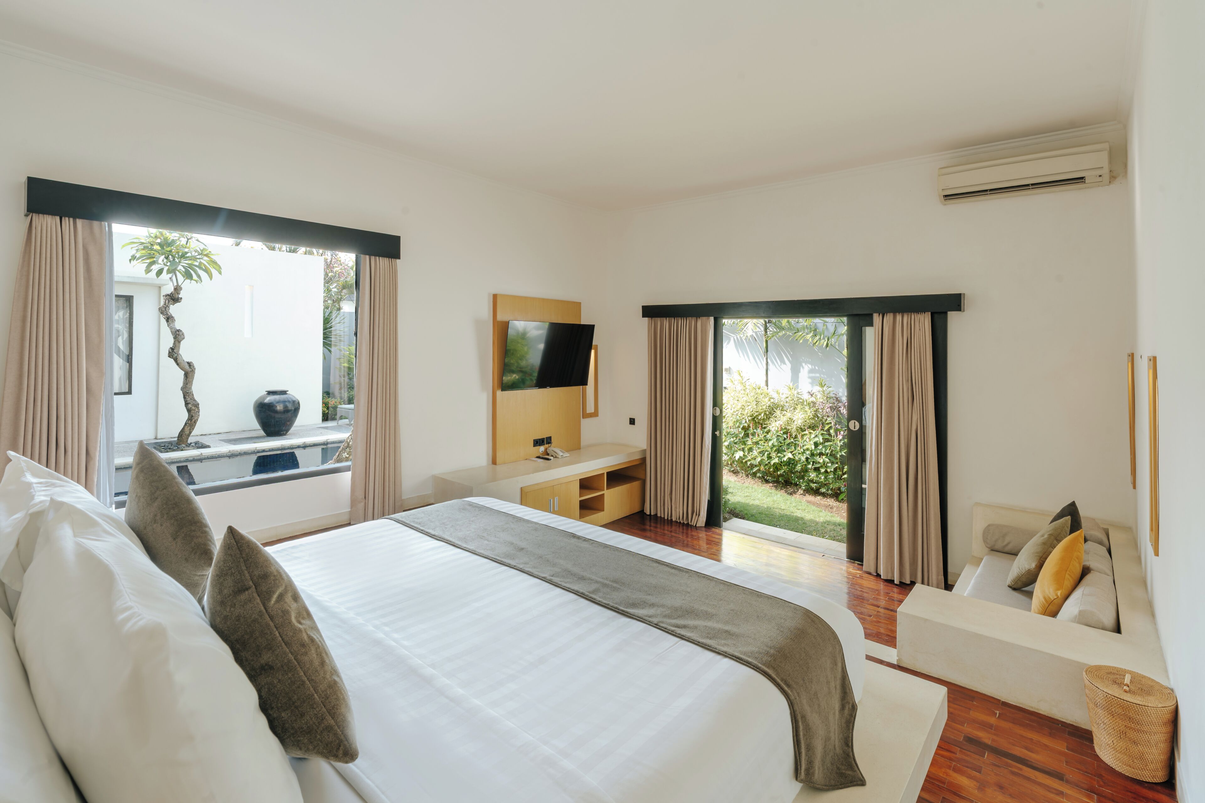 A modern hotel room with a large bed, a TV, a desk, and a sofa.