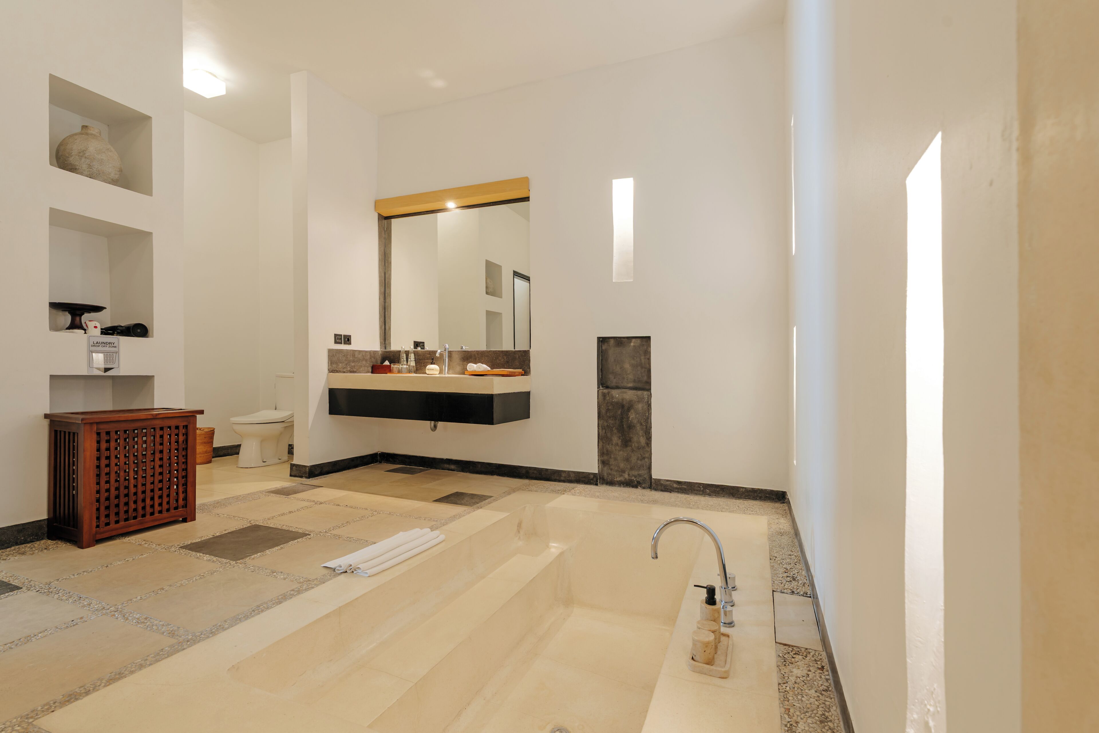Ein modernes Badezimmer mit einer großen Badewanne, einem Waschtisch inklusive Spiegel und einer Toilette.