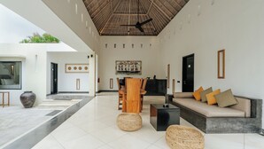 A modern interior with a dining area, a sofa set, and a ceiling fan. - The Seminyak Suites Private Villas  (Seminyak)