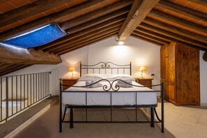 A bedroom with a sloped ceiling, a bed with a metal frame, two bedside lamps, and a wooden wardrobe. - Apartment 'Papavero' with Shared Pool, Wi-Fi and Air Conditioning (Santa luce)