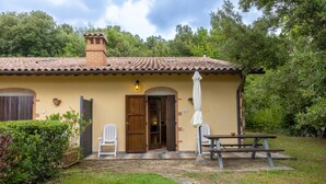 A house with a tiled roof, a wooden door, a bench, and a table.