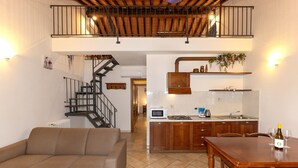 A modern kitchen with wooden cabinets, a dining table, and a staircase leading to an upper level.