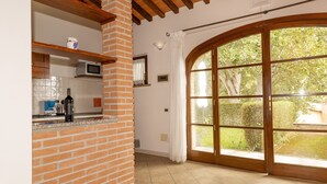 A kitchen with a brick column, a microwave, and a large window with a view of greenery. - Apartment 'Fiordaliso' with Shared Pool, Wi-Fi and Air Conditioning (Santa luce)