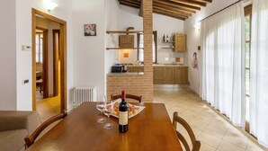 A dining area with a table set for two, a wine bottle, and a view into the kitchen. - Apartment 'Magnolia' with Shared Pool, Wi-Fi and Air Conditioning (Santa luce)