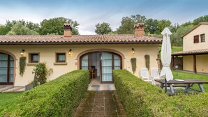 A house with a tiled roof, a covered entrance, and a paved pathway leading to a patio area with a table and chairs. - Apartment 'Magnolia' with Shared Pool, Wi-Fi and Air Conditioning (Santa luce)