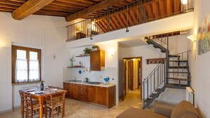 A spacious kitchen with wooden cabinets, a dining table, and a staircase leading to an upper level. - Apartment 'Biancospino' with Shared Pool, Wi-Fi, and Air Conditioning (Santa luce)
