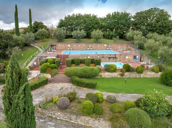 A swimming pool with a deck, surrounded by well-maintained hedges and trees.