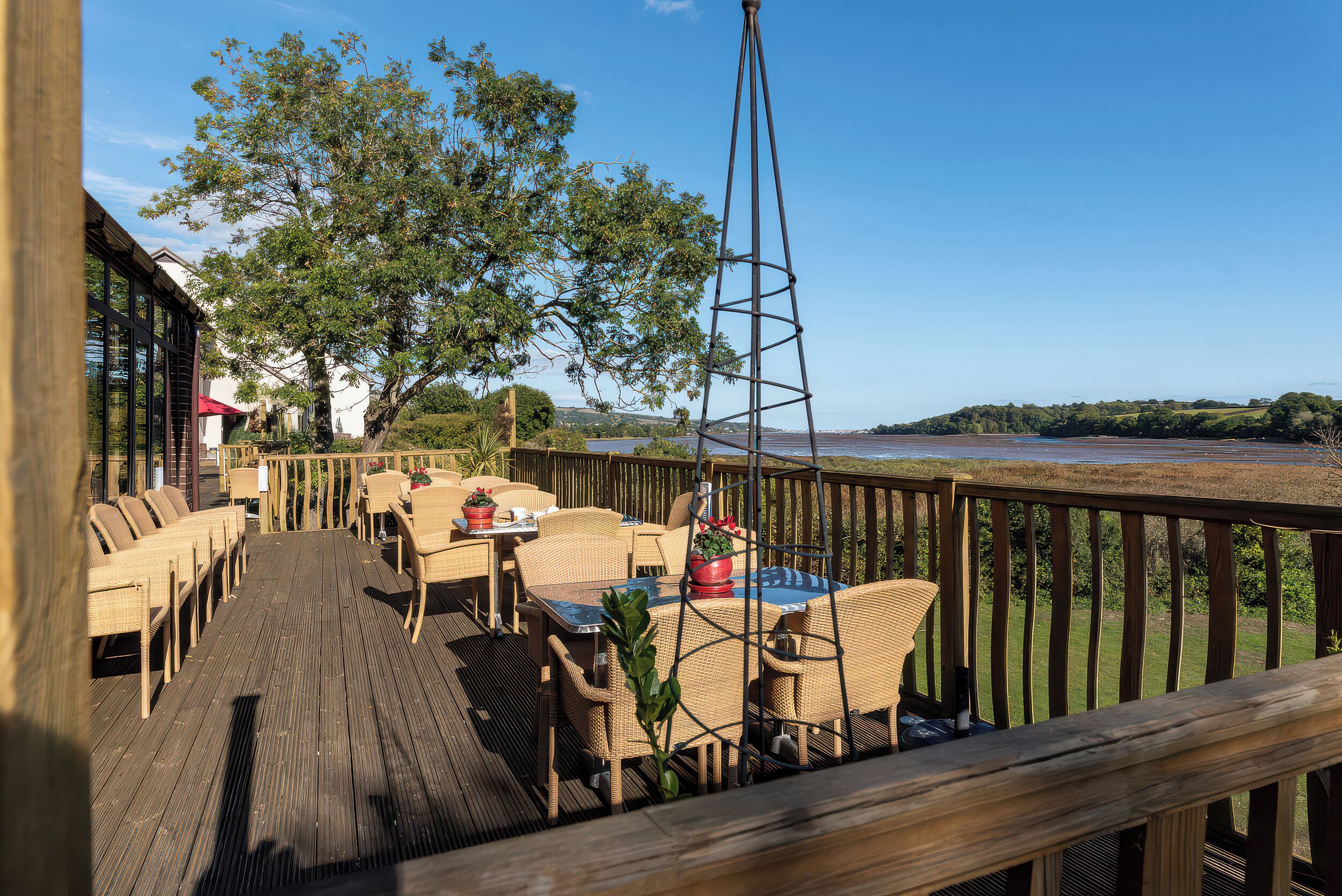 A wooden deck with wicker furniture, a metal tower, and a view of the water.