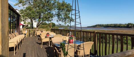 A wooden deck with wicker furniture, a metal tower, and a view of the water.