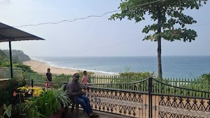 A paved walkway with a metal fence, a bench, and potted plants. - hillview beach resort (Varkala)