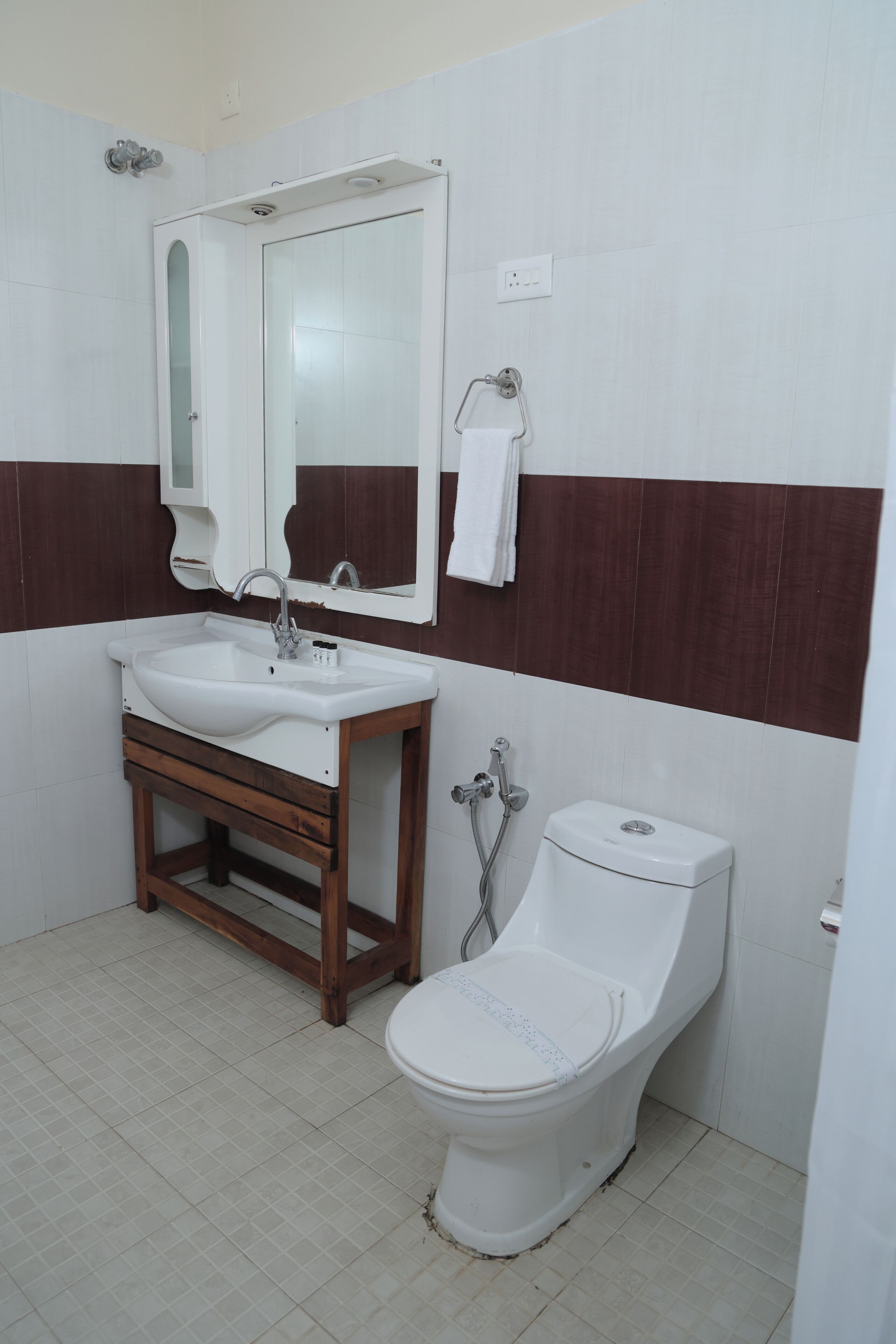 Une salle de bain avec un lavabo, un miroir et des toilettes, le tout de couleur blanche.