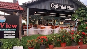 Cafe del Mar with a white fence, potted plants, and a sign for View Beach Resort. - hillview beach resort (Varkala)