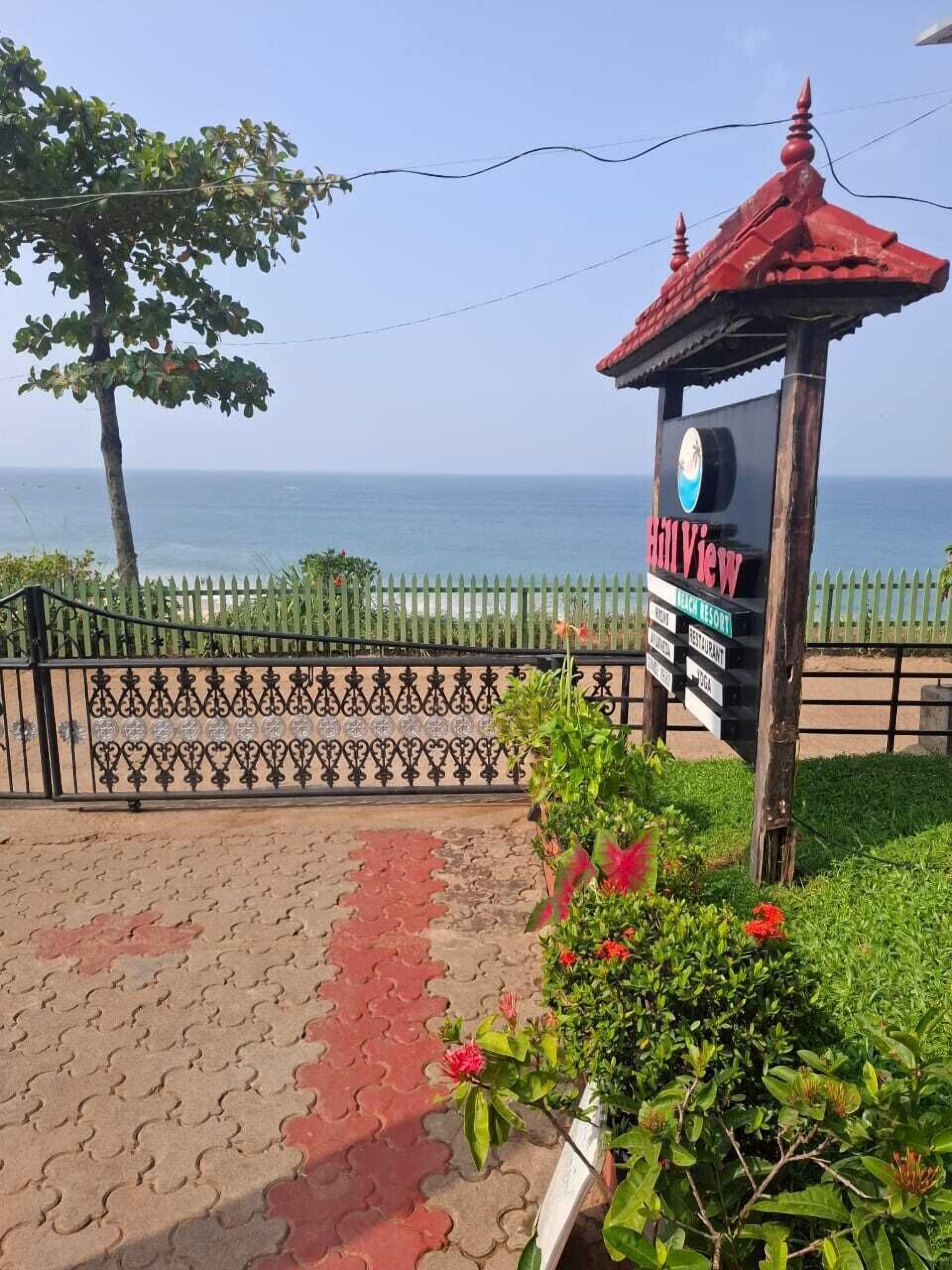 A beach resort sign with a view of the ocean.