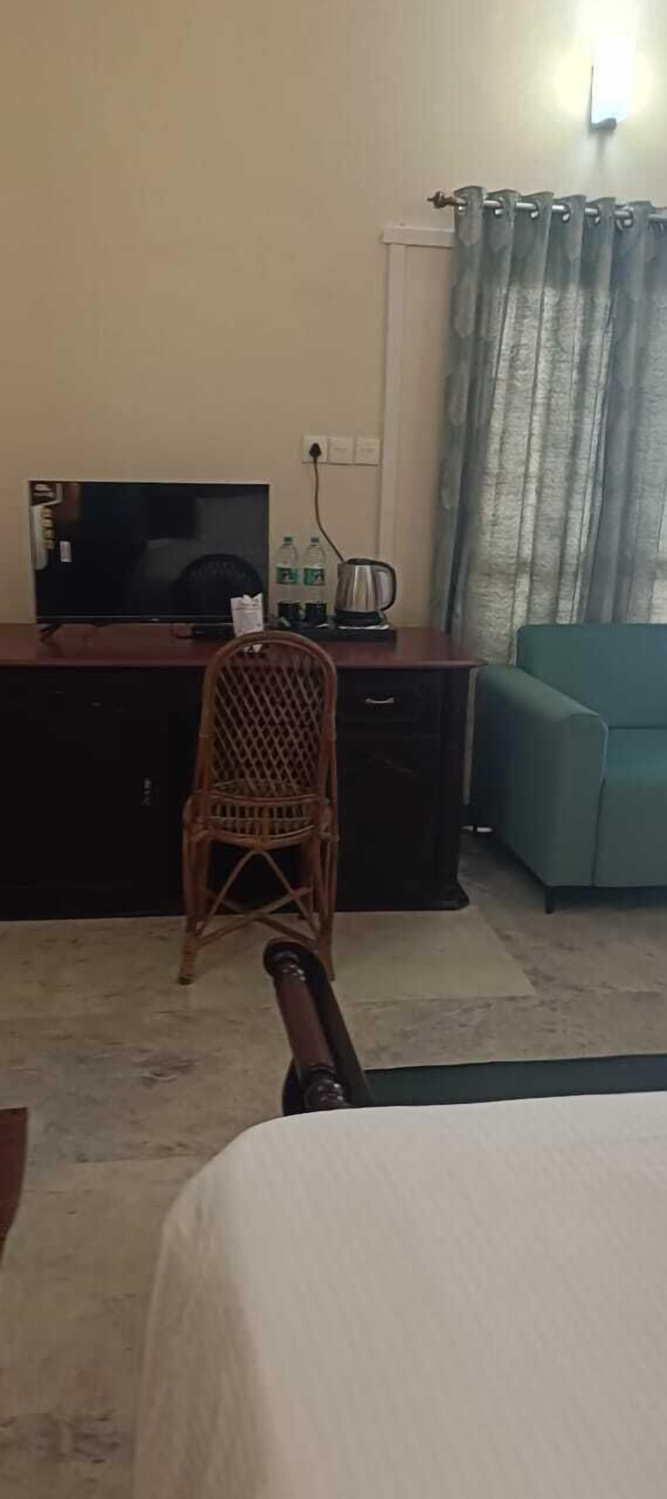 A room with a television, wicker chair, sofa, and a bed.