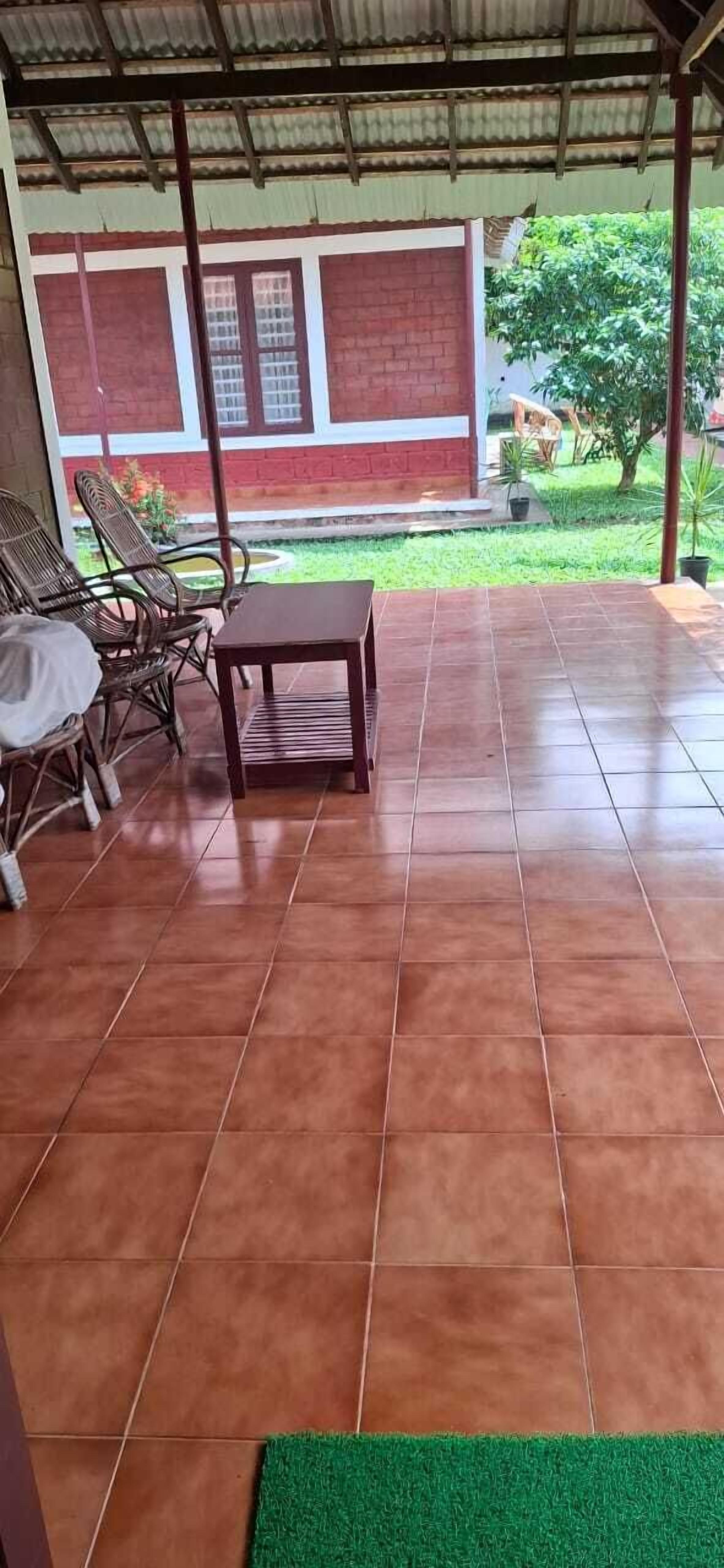 A covered patio area with tiled flooring, a small table, and wicker chairs.