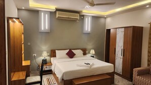 A modern bedroom with a large bed, bedside lamps, an air conditioning unit, and a wardrobe. - hillview beach resort (Varkala)