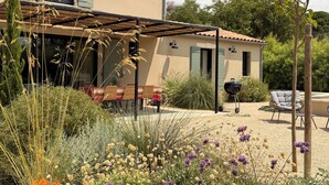 Une maison dotée d’un patio couvert, d’un espace salon extérieur et d’un coin barbecue.